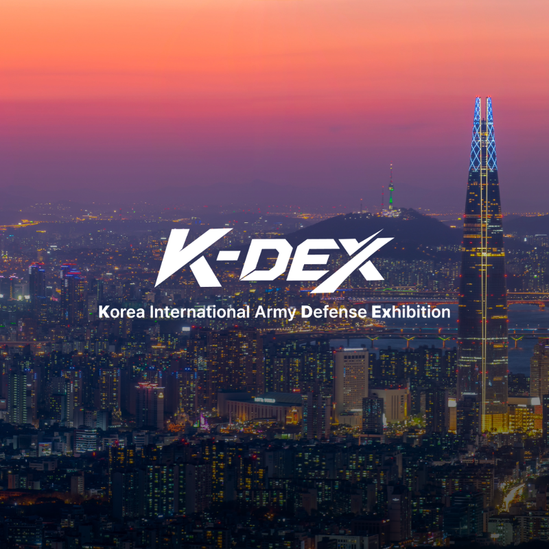 Logo for K-DEX, the Korea International Army Defense Exhibition, overlaid on a twilight aerial view of the Seoul skyline.