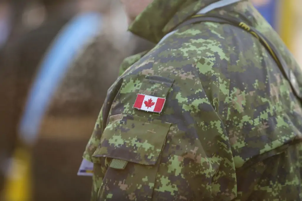 Une personne portant un uniforme de camouflage de l'armée canadienne avec un écusson du drapeau canadien sur la manche.
