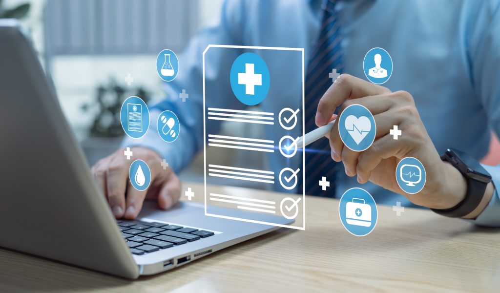 A person using a laptop with digital health and medical icons, including a checklist and healthcare symbols, overlaid in a virtual interface.