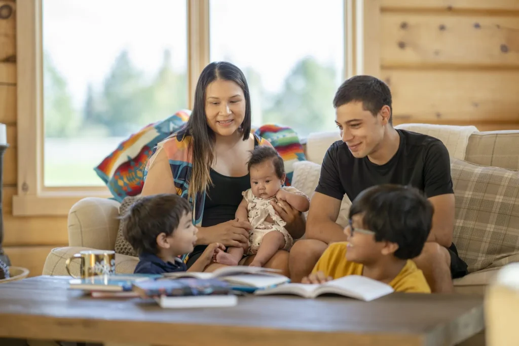 A family sits on a couch and reads a book.