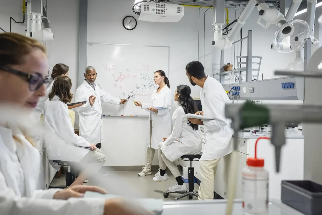 A research group of people in lab coats talking to each other.